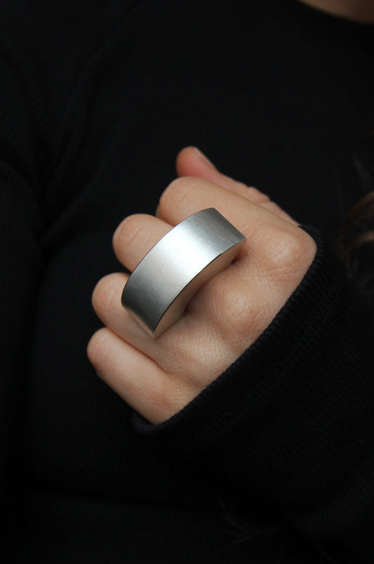 Person wearing a large silver ring on a dark background